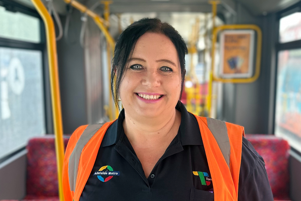 Image of a female tram driver posing in the middle isle of the tram.