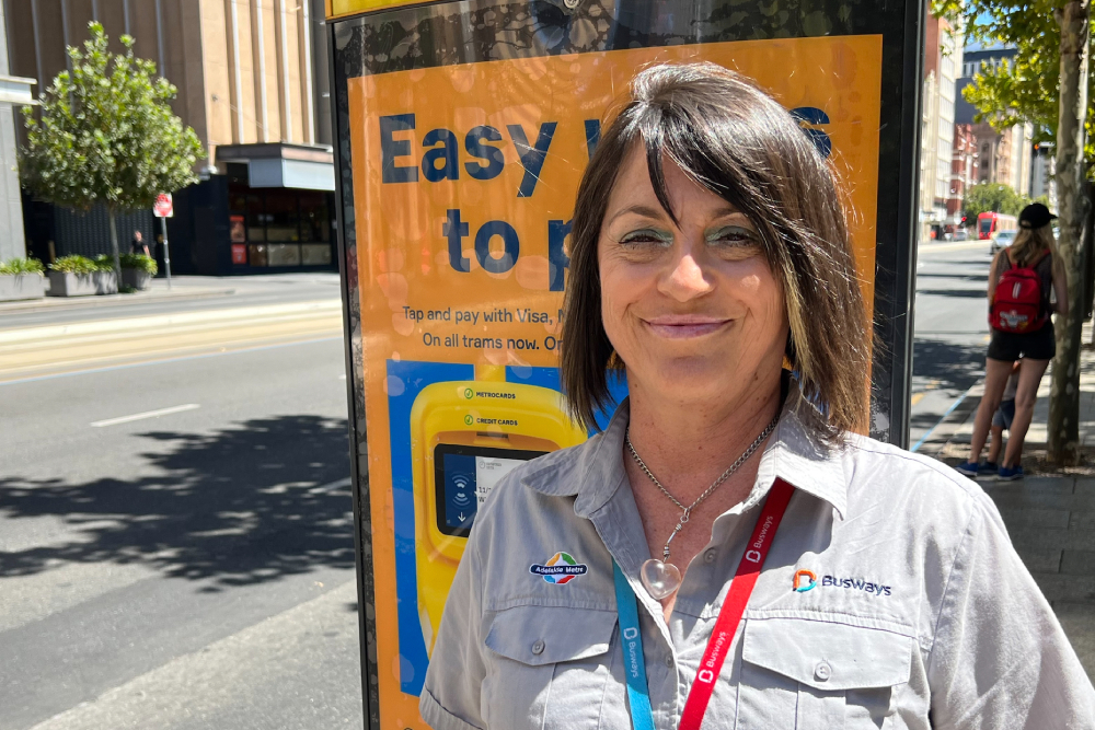 Image of a female bus driver posing in front of a bus stop.