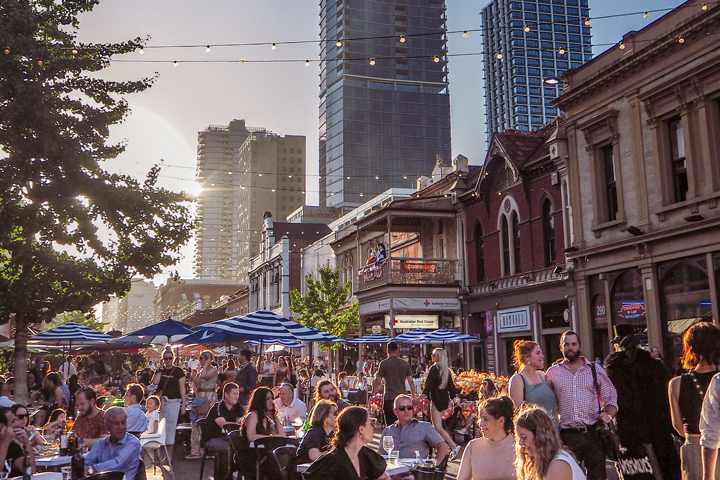 A shot of Rundle Street in Adelaide with a large crowd of people sitting at tables under the sunset.